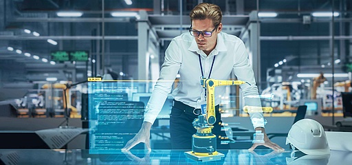 Mann in einem modernen Industriebüro arbeitet mit einem holographischen Interface und einem Roboterarm