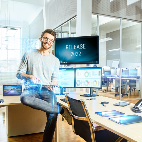 Mann im Technologiebüro vor Bildschirmen mit Release-Ankündigung "Release 2022"