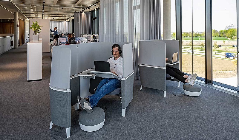 Mitarbeiter arbeiten in modernen Arbeitskabinen in der baramundi SoftwareFactory