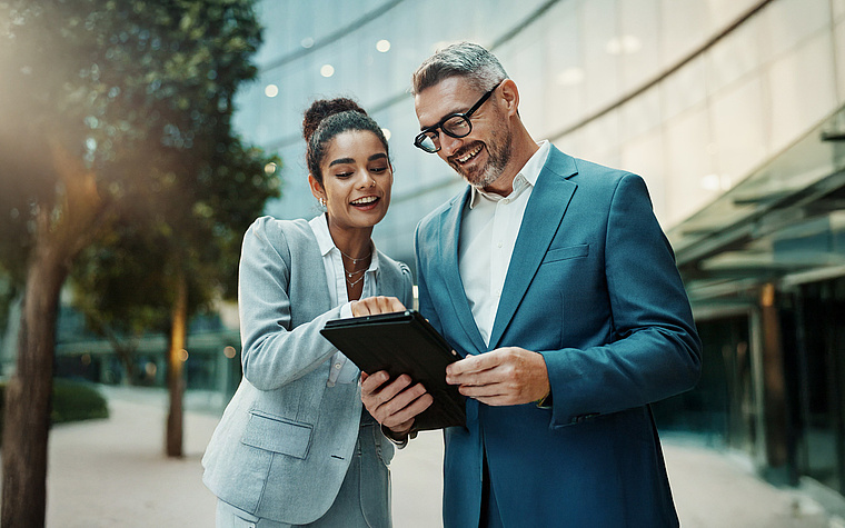 Manager e manager analizzano insieme i dati su un tablet – DEX consente decisioni strategiche informate